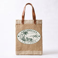A natural jute tote bag with brown leather handles and a green Los Angeles California graphic printed on the front, set against a plain white background.