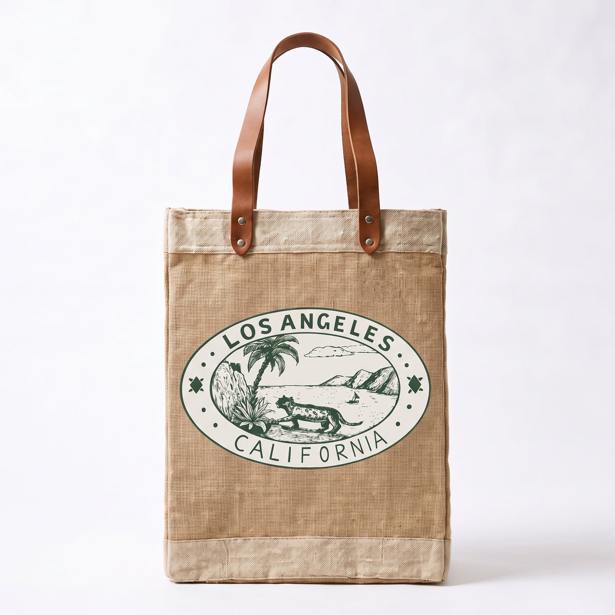 A natural jute tote bag with brown leather handles and a green Los Angeles California graphic printed on the front, set against a plain white background.